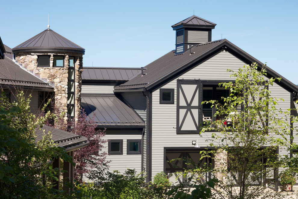 Cette photo montre une grande façade de maison grise nature à un étage avec un revêtement en vinyle et un toit à deux pans.