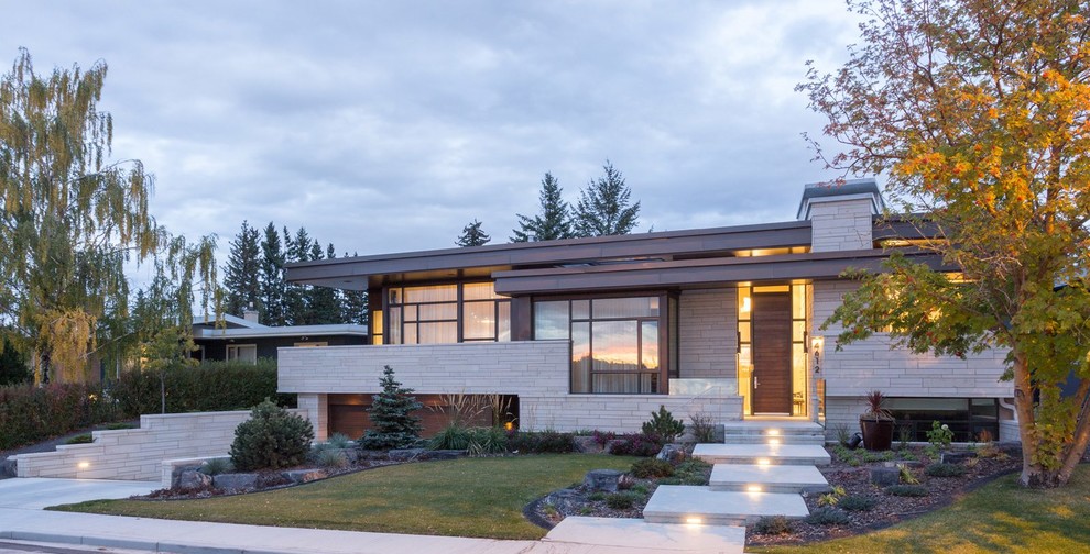 Gey midcentury split-level house exterior in Calgary with mixed cladding and a flat roof.