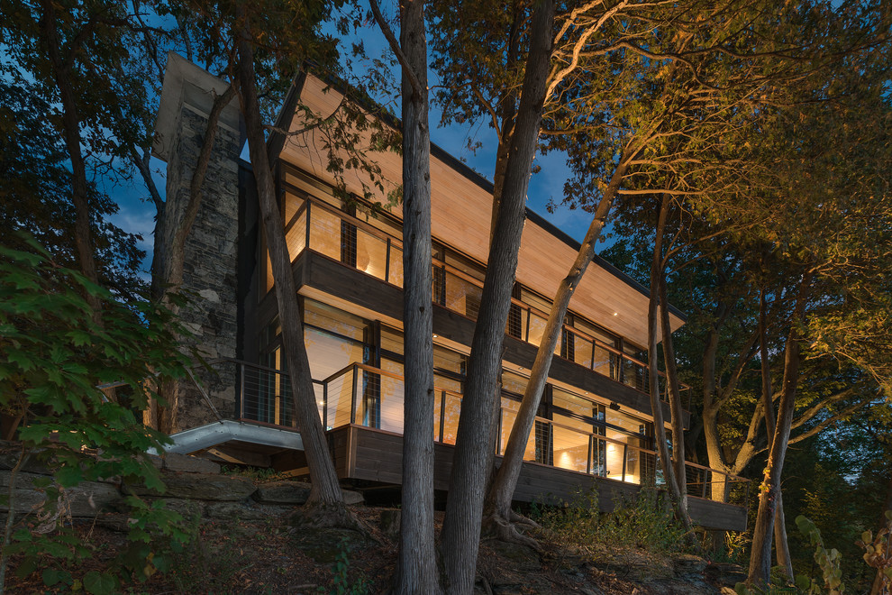 Imagen de fachada de casa marrón rústica de dos plantas con revestimiento de madera y tejado plano