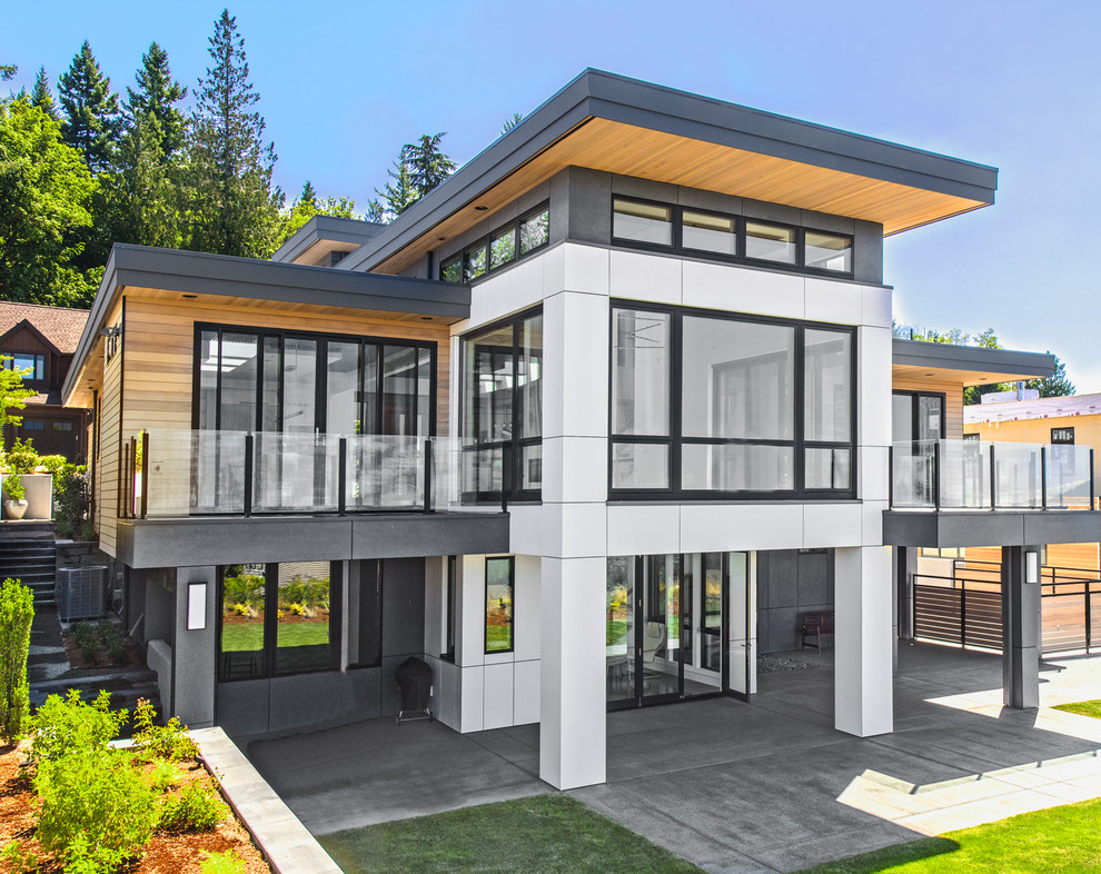 На фото: большой, двухэтажный, разноцветный частный загородный дом в современном стиле с комбинированной облицовкой, плоской крышей и металлической крышей