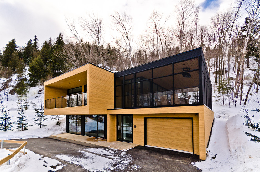 Inspiration for a contemporary two floor house exterior in Montreal with wood cladding.