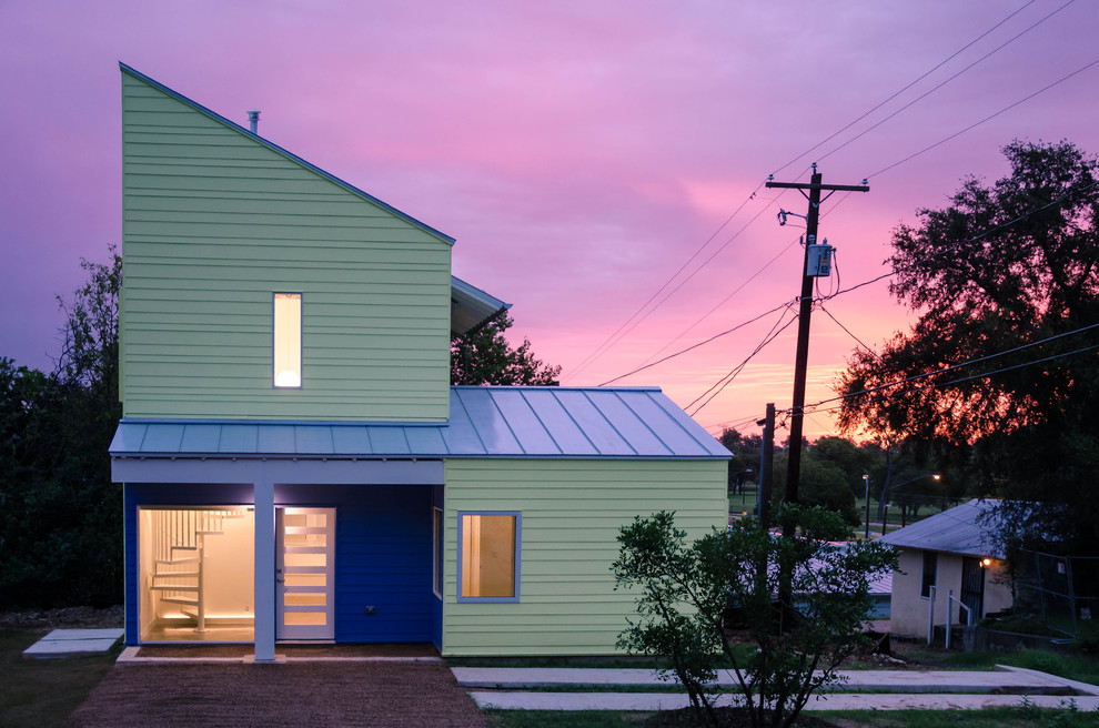 Cette photo montre une façade de maison verte tendance à un étage avec un toit en appentis et un toit bleu.