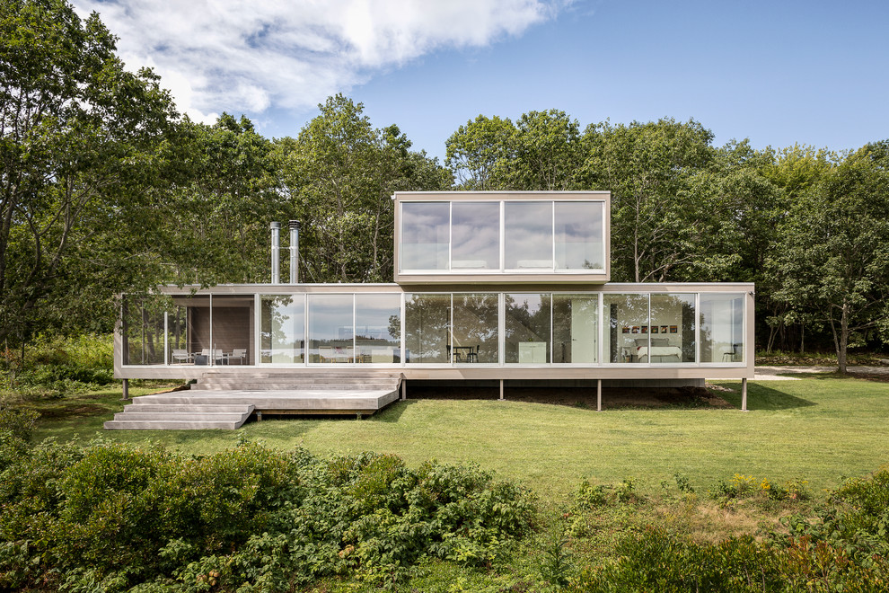 Photo of a contemporary two floor glass house exterior in Portland Maine with a flat roof.
