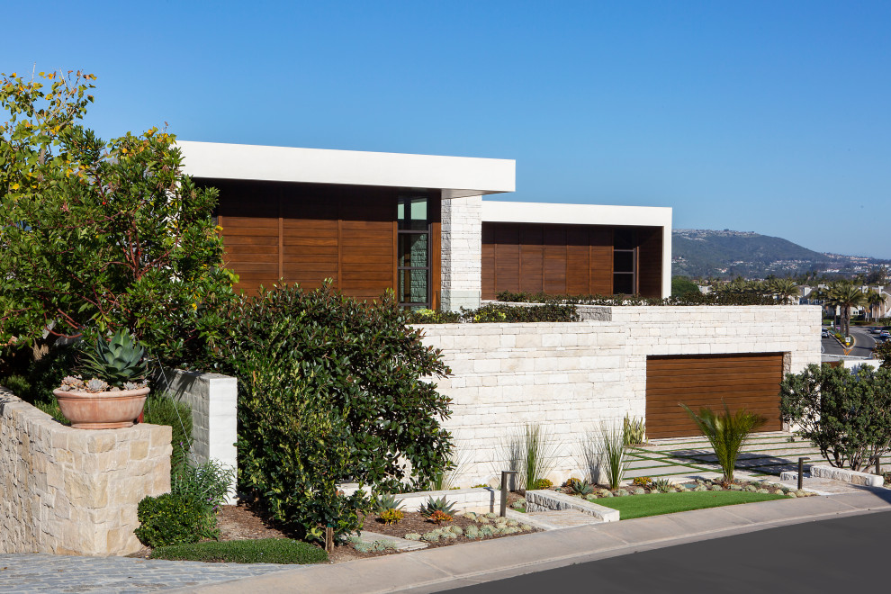 Imagen de fachada de casa blanca contemporánea de dos plantas con revestimiento de piedra y tejado plano