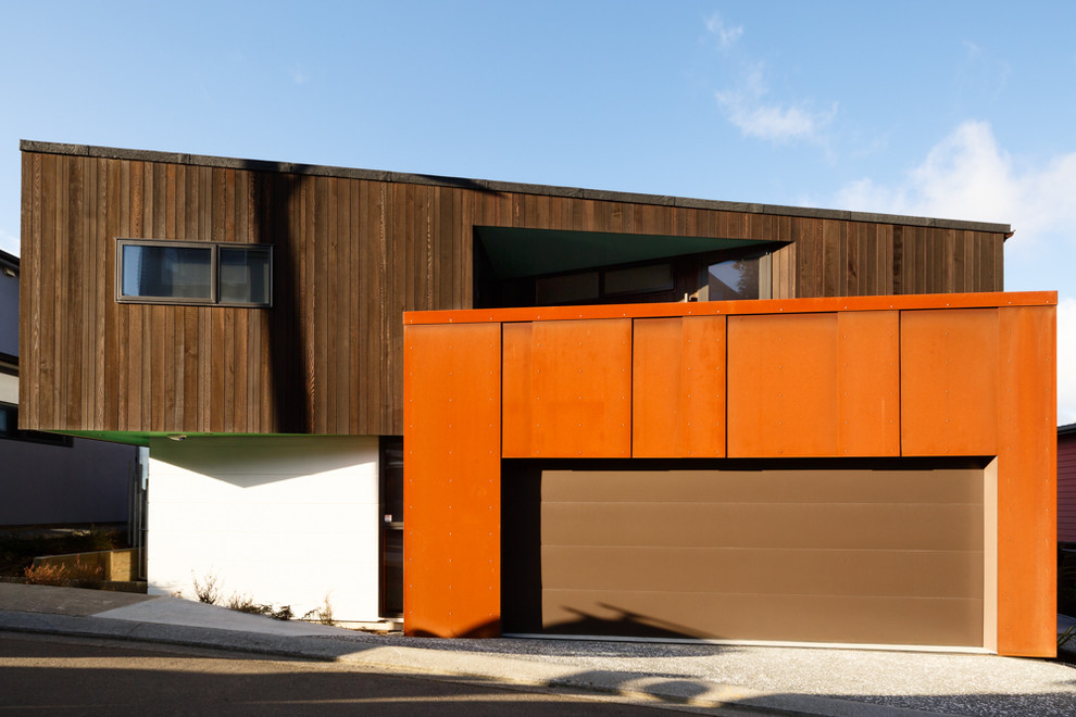 Inspiration för ett funkis oranget hus, med två våningar, blandad fasad och pulpettak