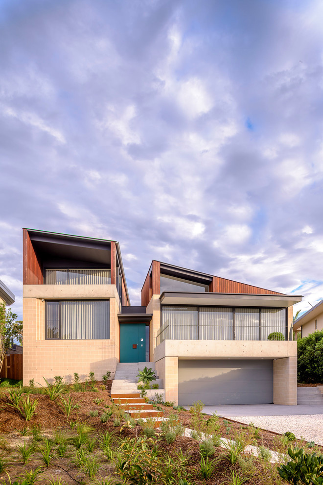 This is an example of a beige contemporary two floor detached house in Sydney with mixed cladding and a lean-to roof.