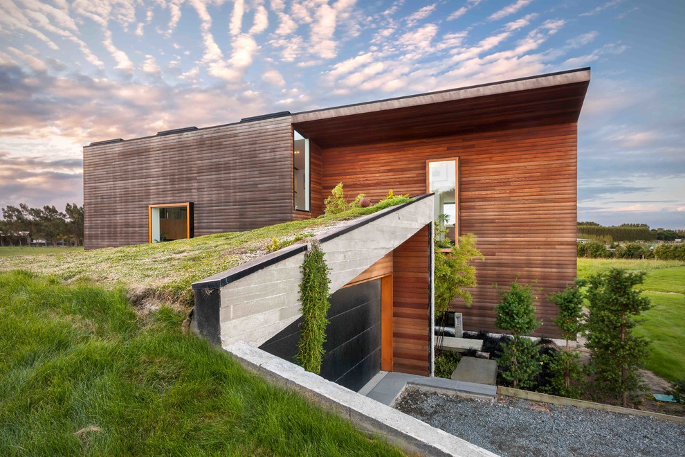 Cette photo montre une façade de maison tendance en bois à un étage avec un toit plat et un toit végétal.