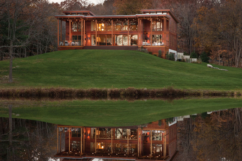 Cette image montre une grande façade de maison marron design en bois à un étage avec un toit en appentis.