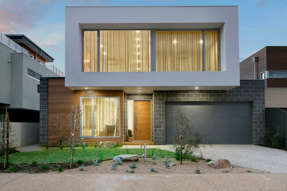Foto de fachada de casa gris actual de dos plantas con revestimientos combinados y tejado plano