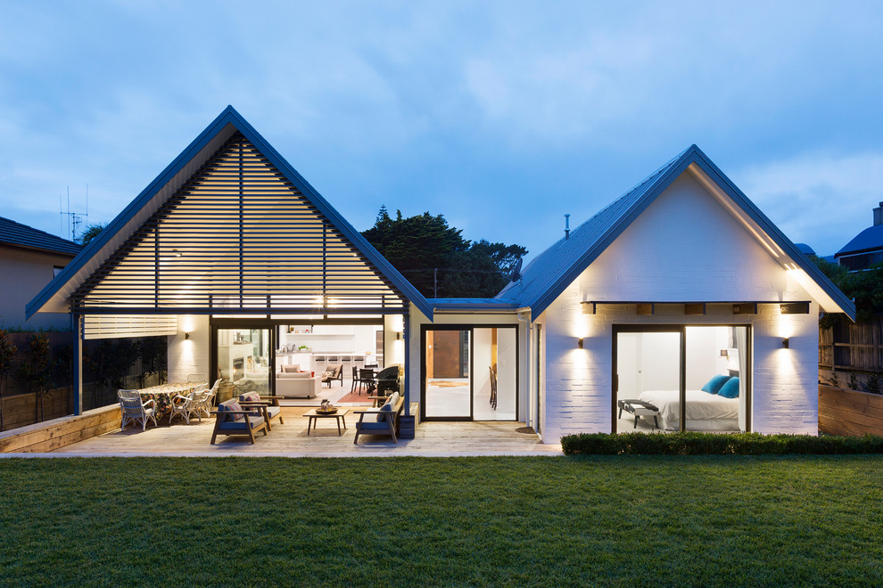 Large and white contemporary bungalow brick house exterior in Other with a pitched roof.