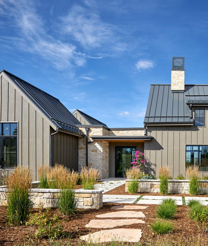 На фото: большой, двухэтажный, коричневый частный загородный дом в стиле кантри с комбинированной облицовкой, двускатной крышей и металлической крышей с