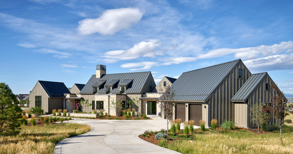 Foto della villa grande marrone country a due piani con rivestimenti misti, tetto a capanna e copertura in metallo o lamiera