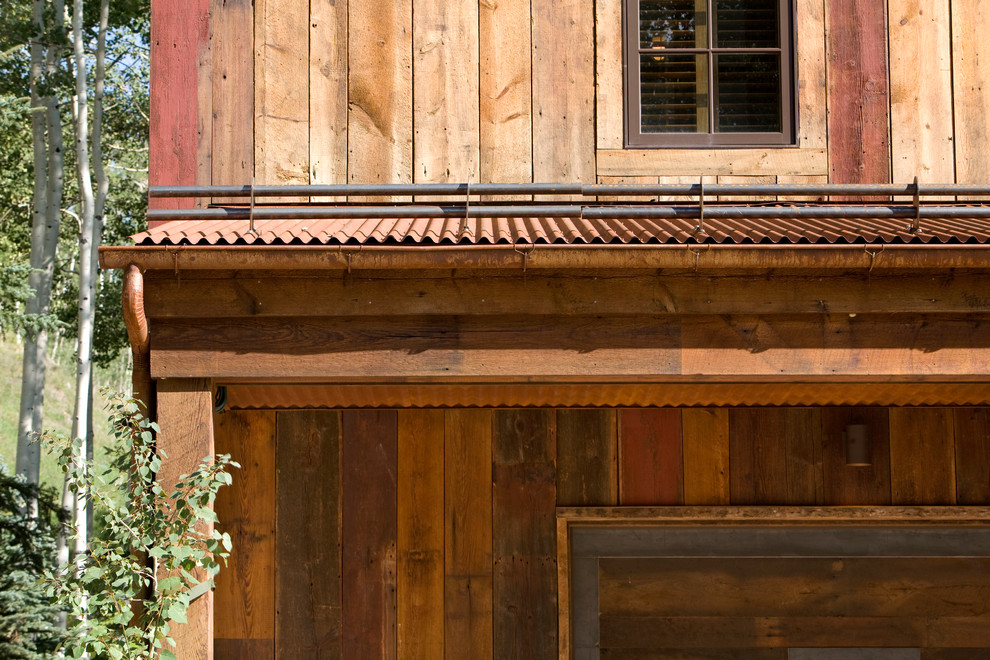 Immagine della facciata di una casa grande marrone rustica a due piani con rivestimento in legno e copertura in metallo o lamiera