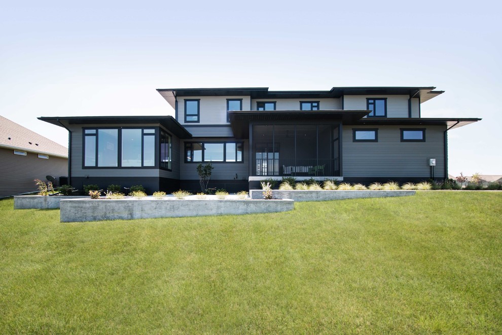 Mittelgroßes, Zweistöckiges Modernes Einfamilienhaus mit grauer Fassadenfarbe, Flachdach, Vinylfassade und Blechdach in Sonstige