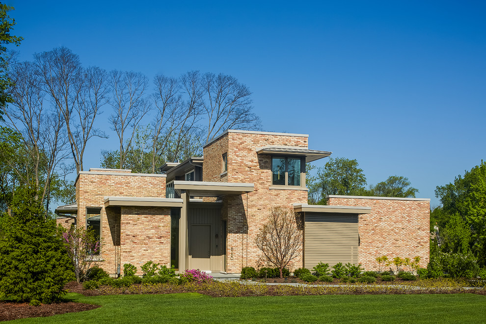 Idée de décoration pour une grande façade de maison rose minimaliste en brique à un étage avec un toit plat.
