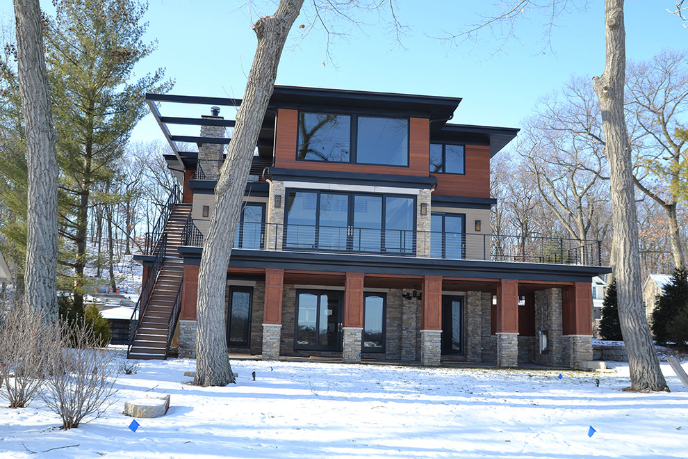 Aménagement d'une grande façade de maison beige contemporaine à deux étages et plus avec un revêtement mixte, un toit plat et un toit en métal.