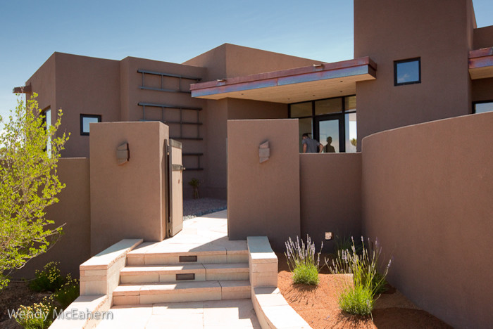 Mid-sized trendy brown one-story stucco flat roof photo in Albuquerque
