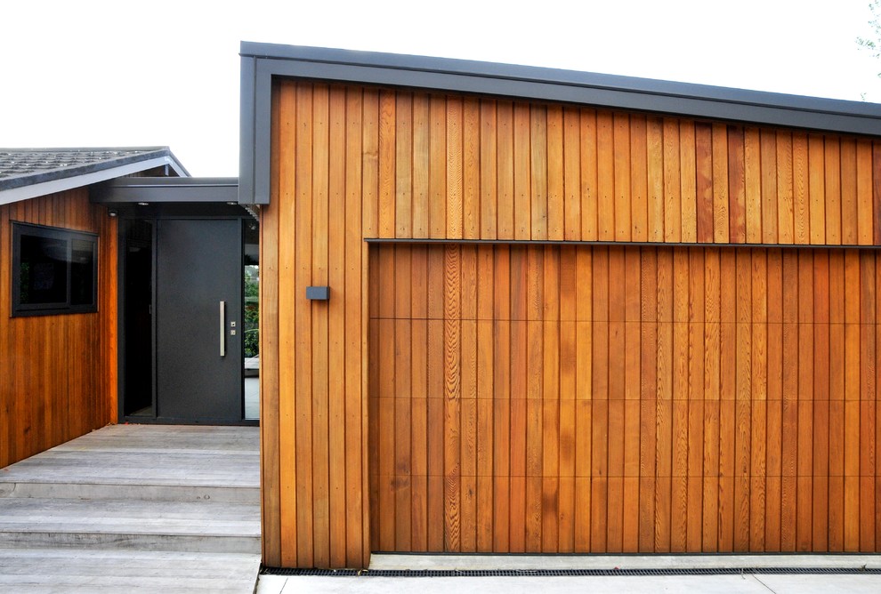 This is an example of a small and brown contemporary bungalow house exterior in Auckland with wood cladding and a lean-to roof.