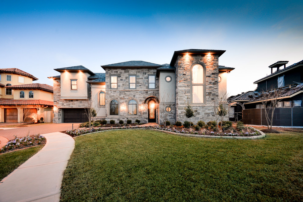 Large contemporary gray two-story stone house exterior idea in Houston with a hip roof and a tile roof