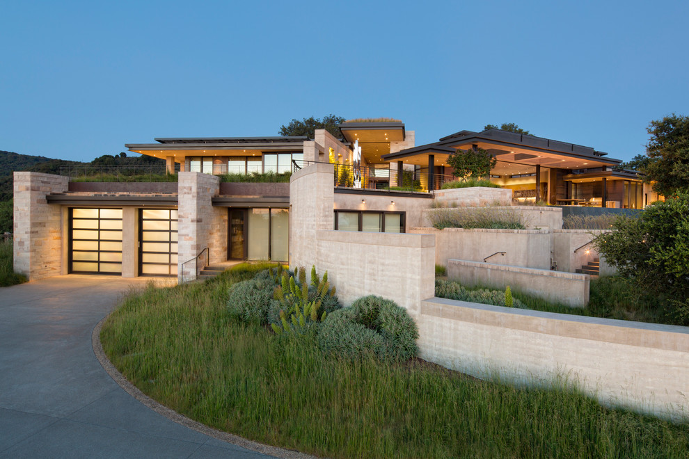 Стильный дизайн: огромный, двухэтажный, бежевый дом в стиле модернизм с облицовкой из камня и плоской крышей - последний тренд