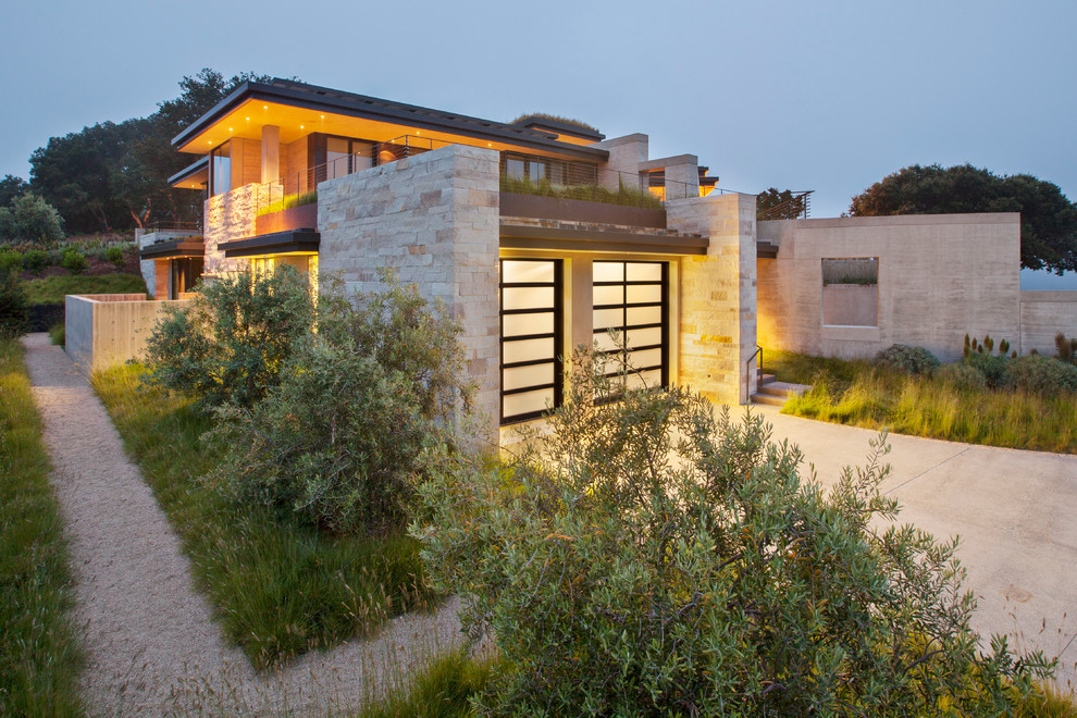 Стильный дизайн: огромный, двухэтажный, бежевый дом в стиле модернизм с облицовкой из камня и плоской крышей - последний тренд