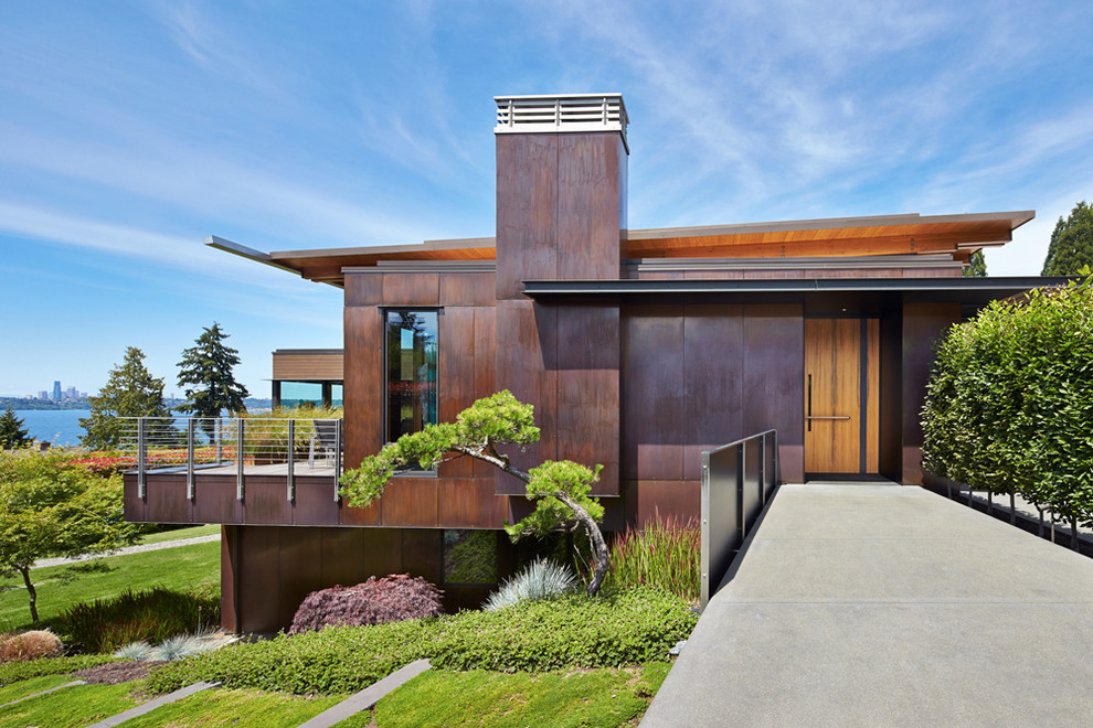 Cette image montre une façade de maison métallique et marron design de taille moyenne et à un étage avec un toit en appentis.