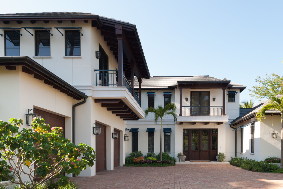 Ejemplo de fachada de casa blanca tropical de dos plantas con tejado a cuatro aguas
