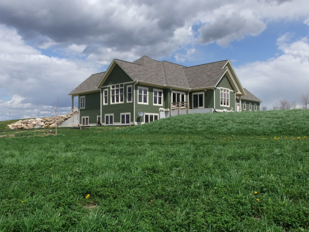 Imagen de fachada de casa verde tradicional grande de dos plantas con revestimiento de aglomerado de cemento, tejado a dos aguas y tejado de teja de barro