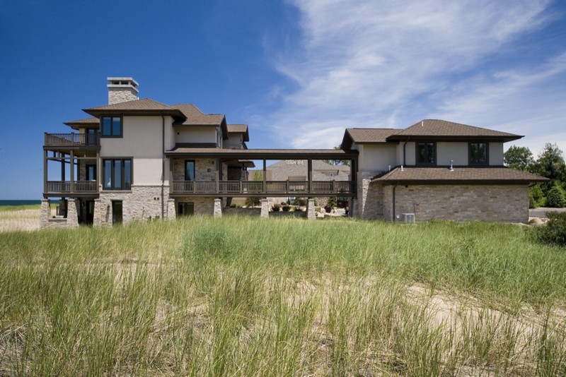 Exemple d'une très grande façade de maison beige tendance en stuc à deux étages et plus avec un toit à quatre pans.