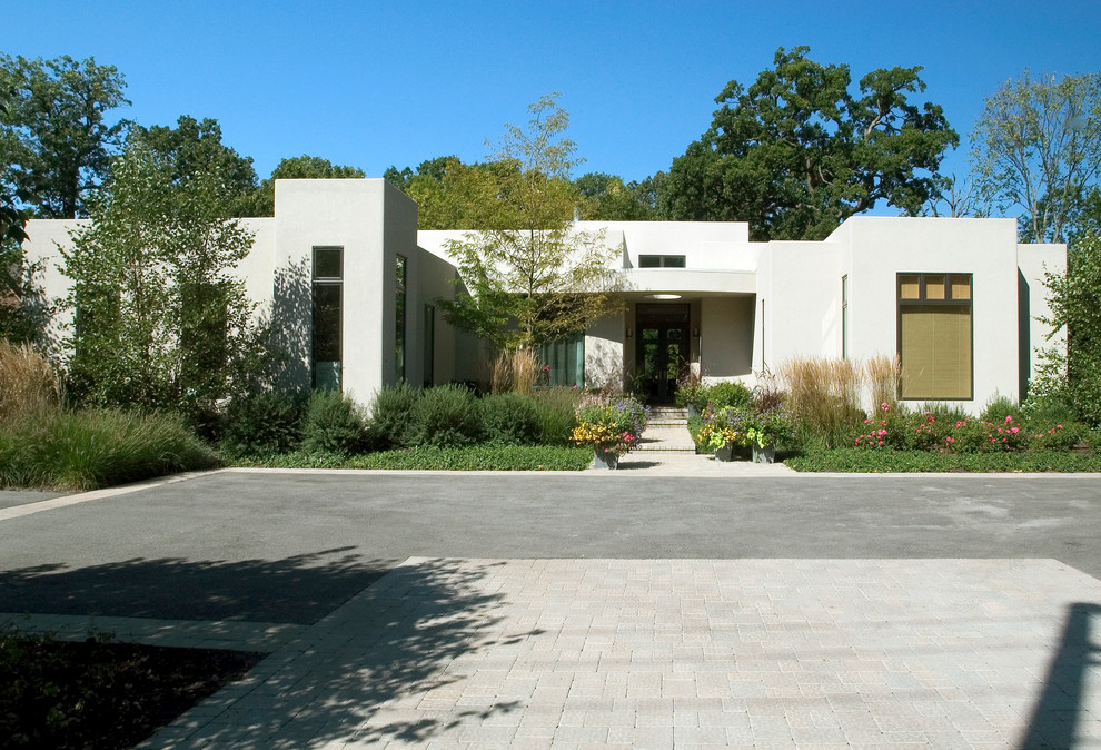 На фото: большой, одноэтажный, бежевый дом в современном стиле с облицовкой из цементной штукатурки и плоской крышей с