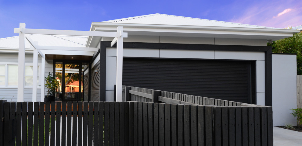 Cette image montre une grande façade de maison grise design de plain-pied avec un toit à quatre pans et un toit en métal.