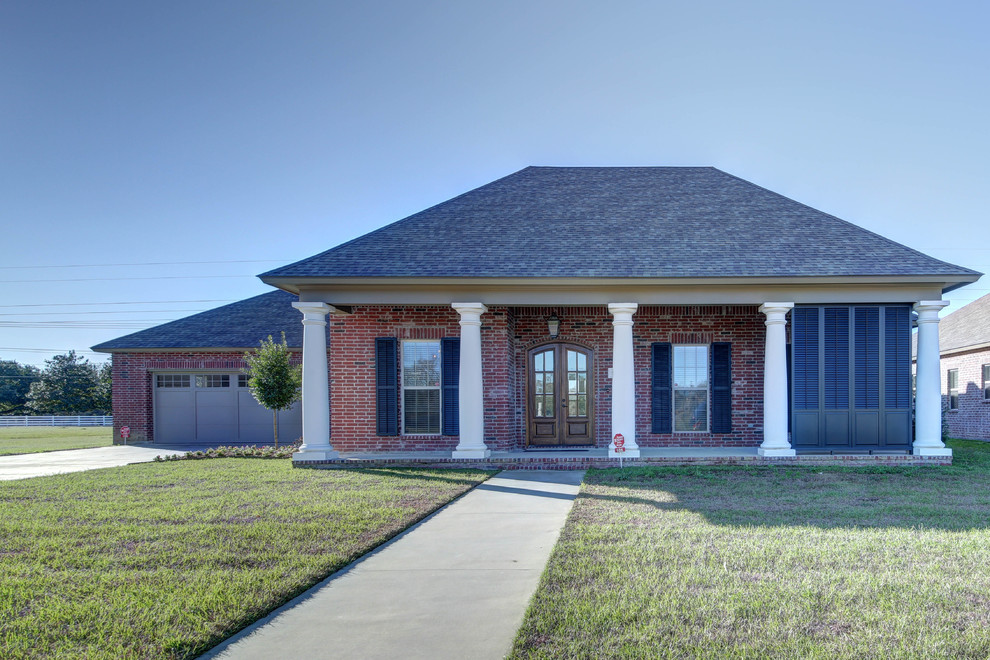 Immagine della facciata di una casa rossa classica a un piano di medie dimensioni con rivestimento in mattoni e tetto a padiglione