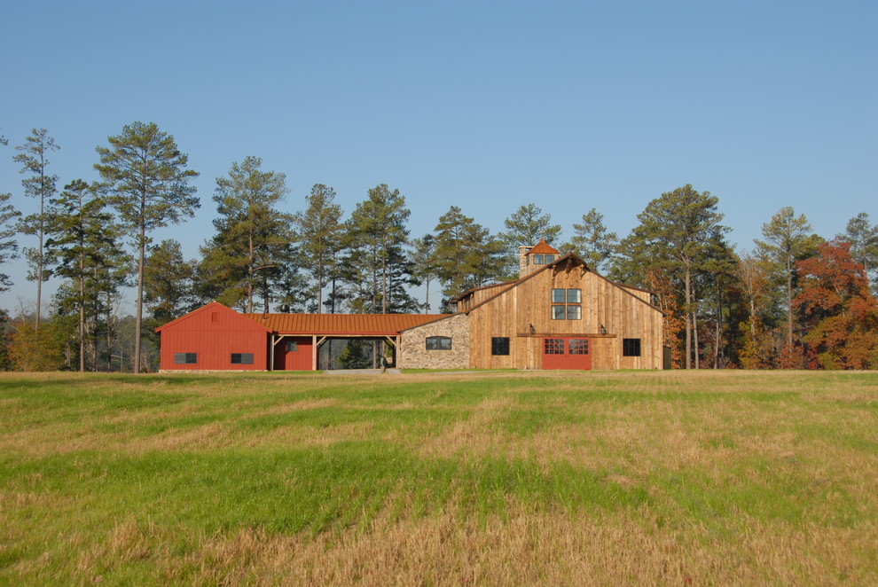 На фото: большой, двухэтажный, деревянный, красный барнхаус (амбары) частный загородный дом в стиле кантри с двускатной крышей и черепичной крышей