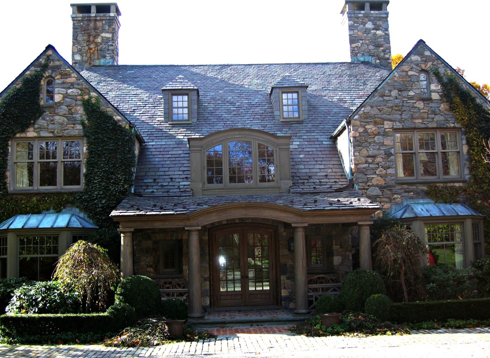 Esempio della facciata di una casa ampia country a tre piani con rivestimento in pietra