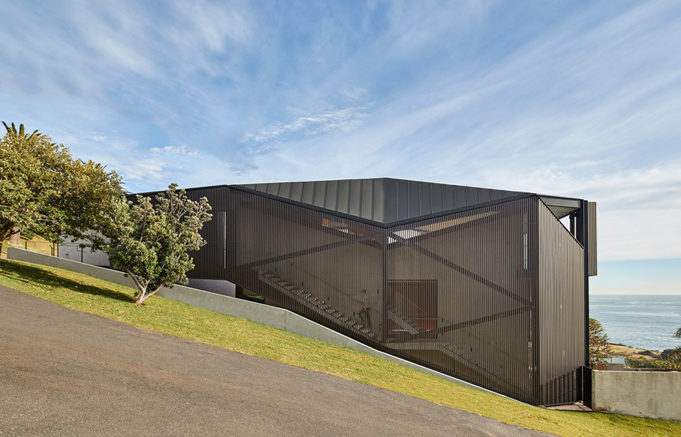 Idée de décoration pour une façade de maison grise minimaliste avec un toit en métal.
