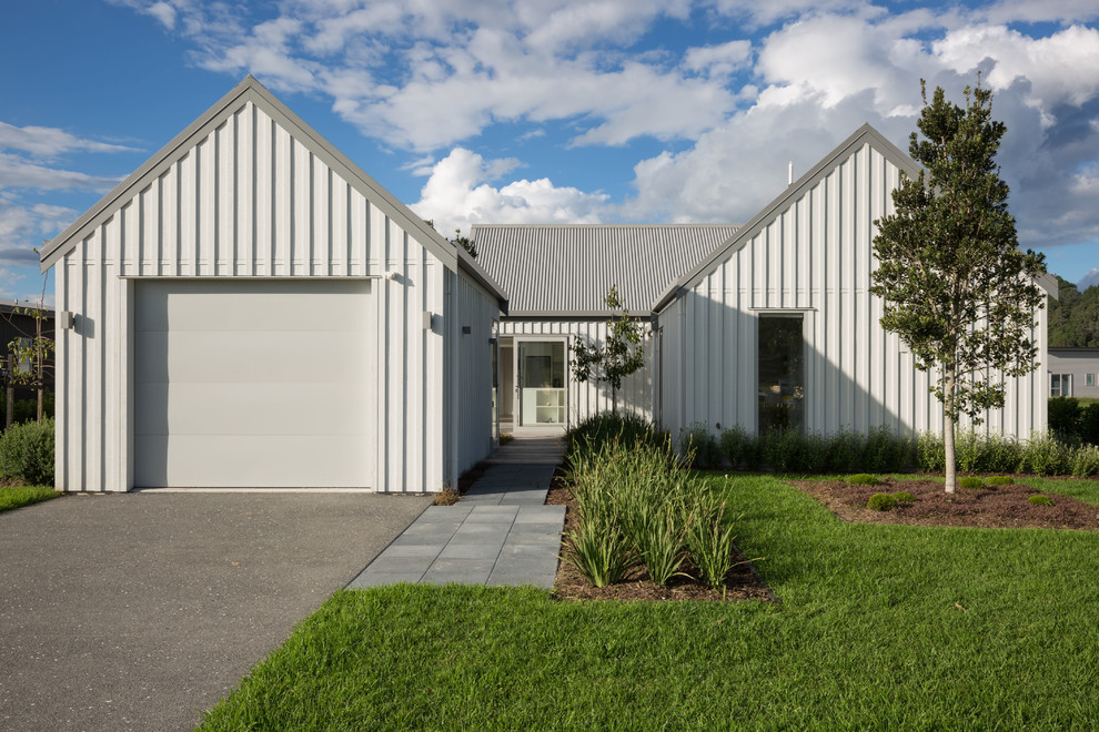 Ejemplo de fachada de casa blanca industrial de tamaño medio de una planta con revestimiento de metal, tejado a dos aguas y tejado de metal