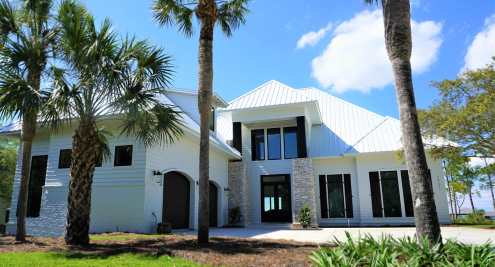 Bild på ett stort tropiskt vitt hus, med valmat tak och tak i metall