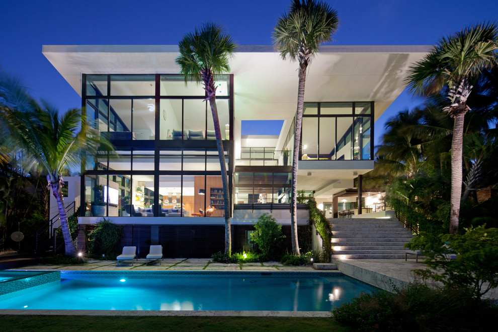 Expansive contemporary two floor glass house exterior in Miami with a flat roof.