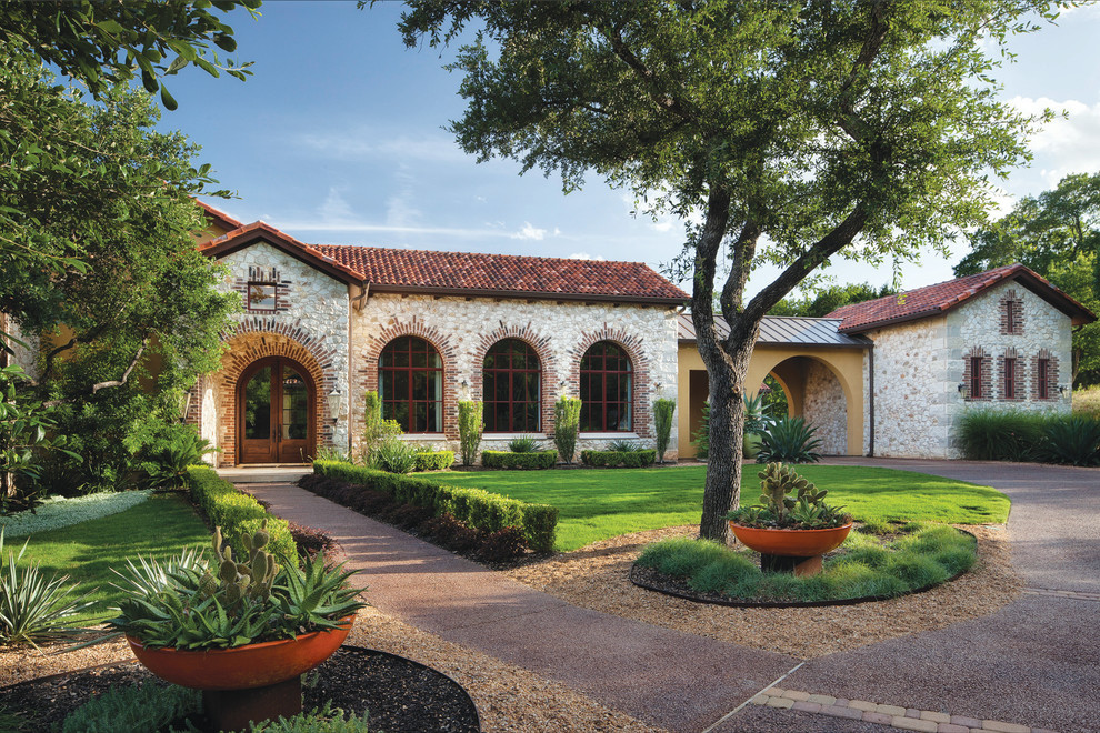 Mediterranean house exterior in Austin with stone cladding and a mixed material roof.