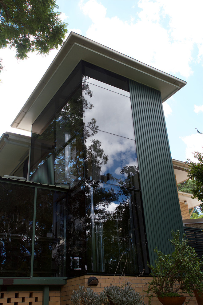 Réalisation d'une grande façade de maison verte design en verre à un étage avec un toit en métal.