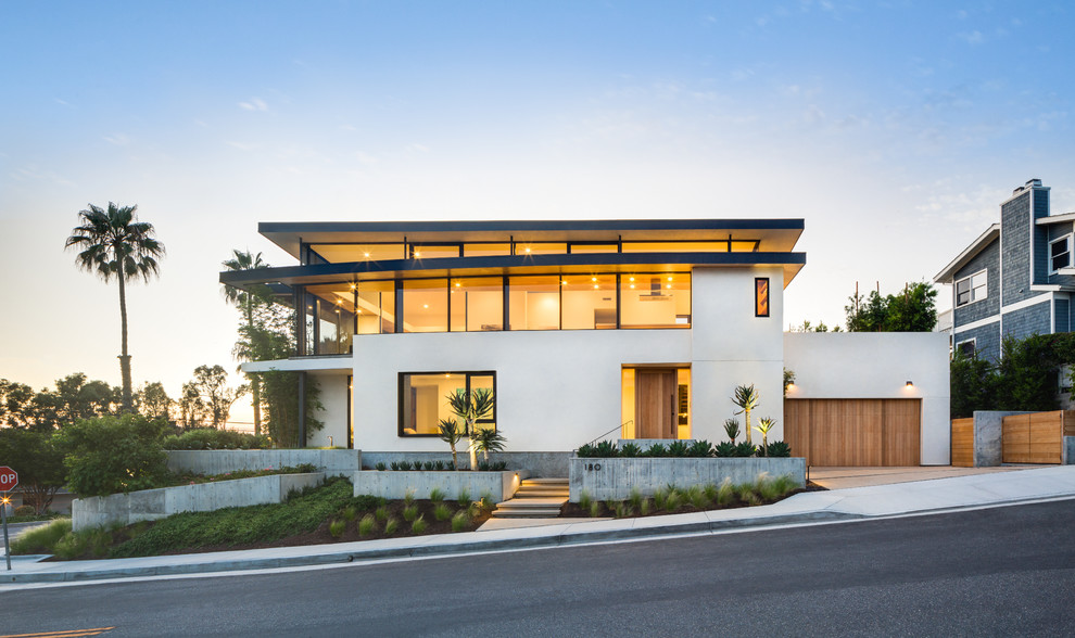Inspiration for a large contemporary white two-story stucco exterior home remodel in Orange County with a mixed material roof