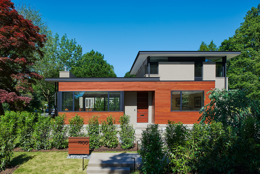Exemple d'une façade de maison grise tendance en stuc de taille moyenne et à un étage avec un toit plat et un toit mixte.