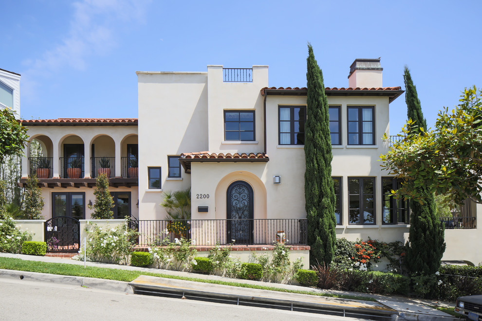 Diseño de fachada de casa beige mediterránea extra grande de dos plantas con revestimiento de estuco, tejado plano y tejado de teja de barro