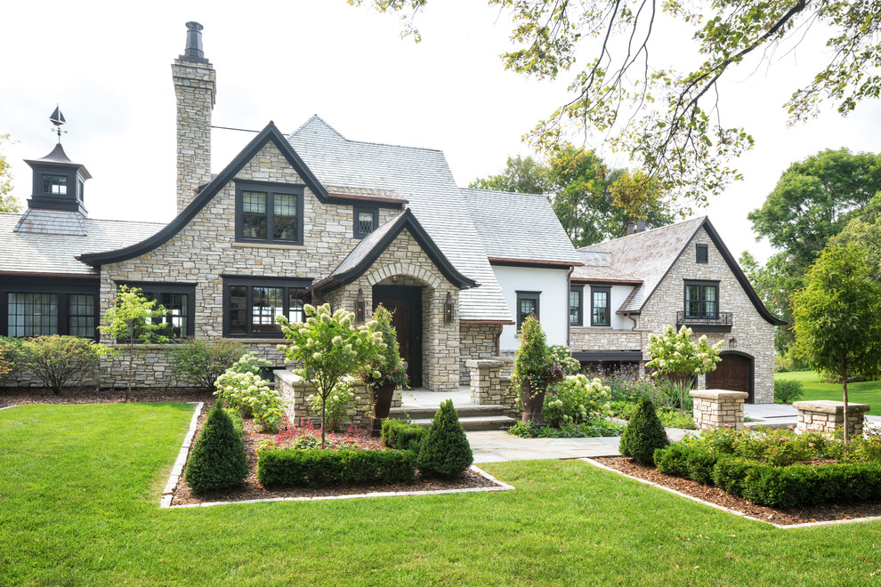 Example of a classic one-story stone exterior home design in Minneapolis with a tile roof