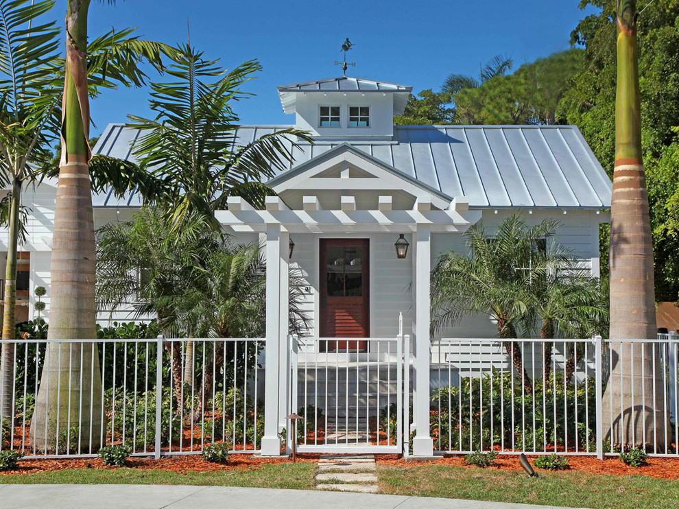 Cette photo montre une façade de maison blanche exotique en bois de plain-pied et de taille moyenne avec un toit à deux pans et un toit en métal.