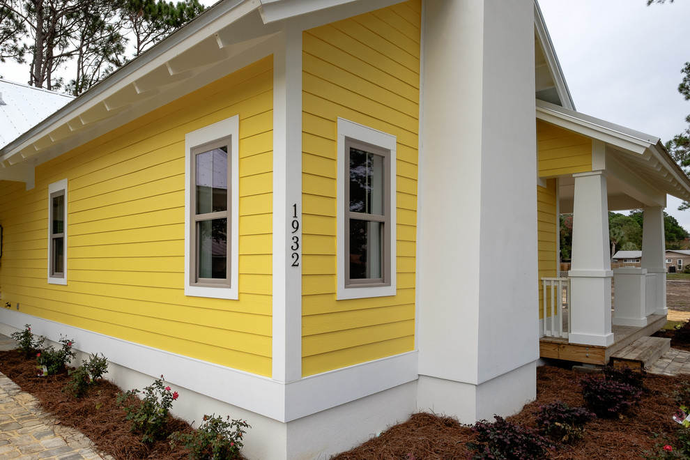 Inspiration for a mid-sized timeless yellow one-story concrete fiberboard gable roof remodel in Miami