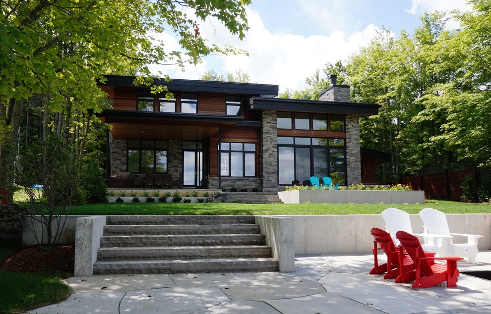 Esempio della facciata di una casa marrone contemporanea a due piani con rivestimenti misti e tetto piano