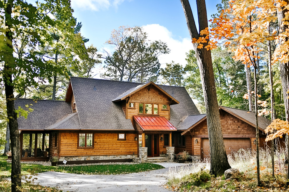 На фото: двухэтажный, деревянный, коричневый частный загородный дом в стиле рустика с двускатной крышей с