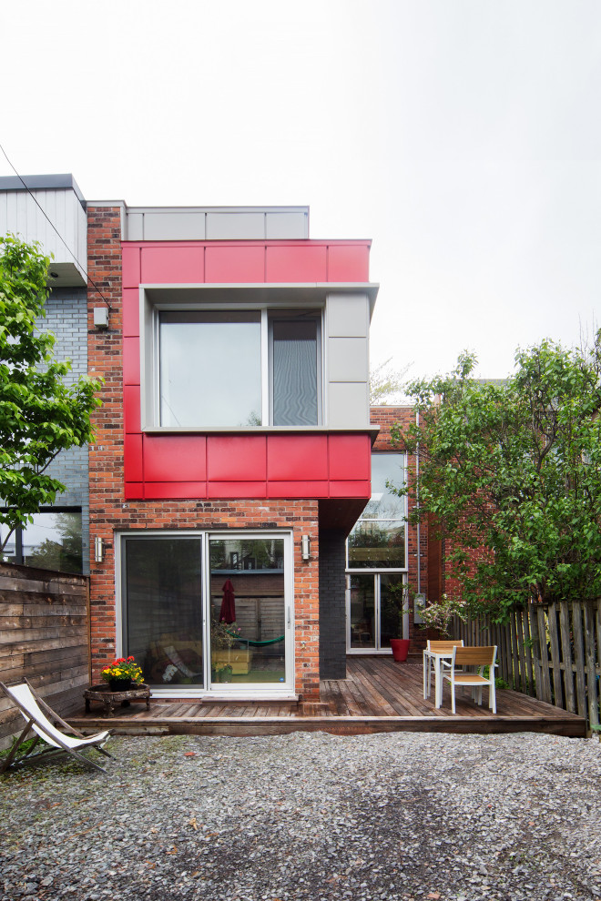 Red contemporary two floor terraced house in Montreal with a flat roof and mixed cladding.