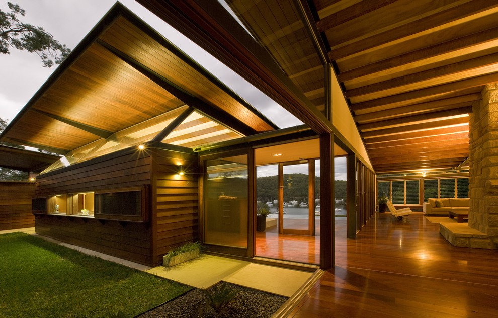 Cette image montre une grande façade de maison marron design en bois à un étage.